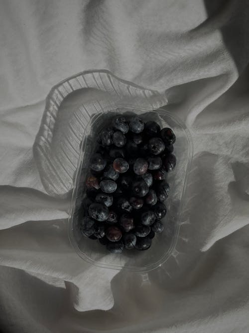 Fresh blueberries in plastic container on white cloth