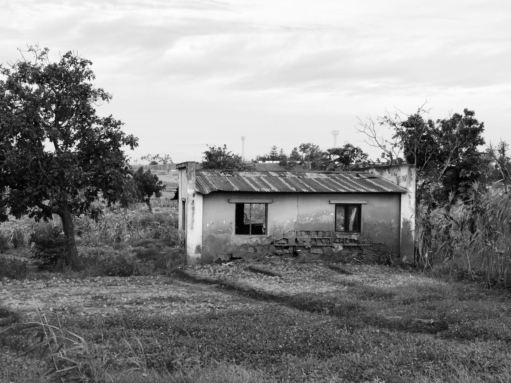Grayscale photo of an abandoned house in a rural landscape in Maputo, Mozambique.