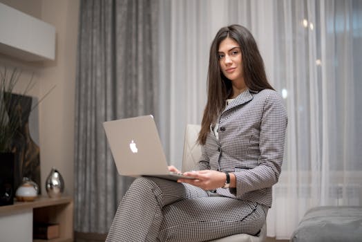 Confident woman using a laptop at home for remote work in a stylish living room.