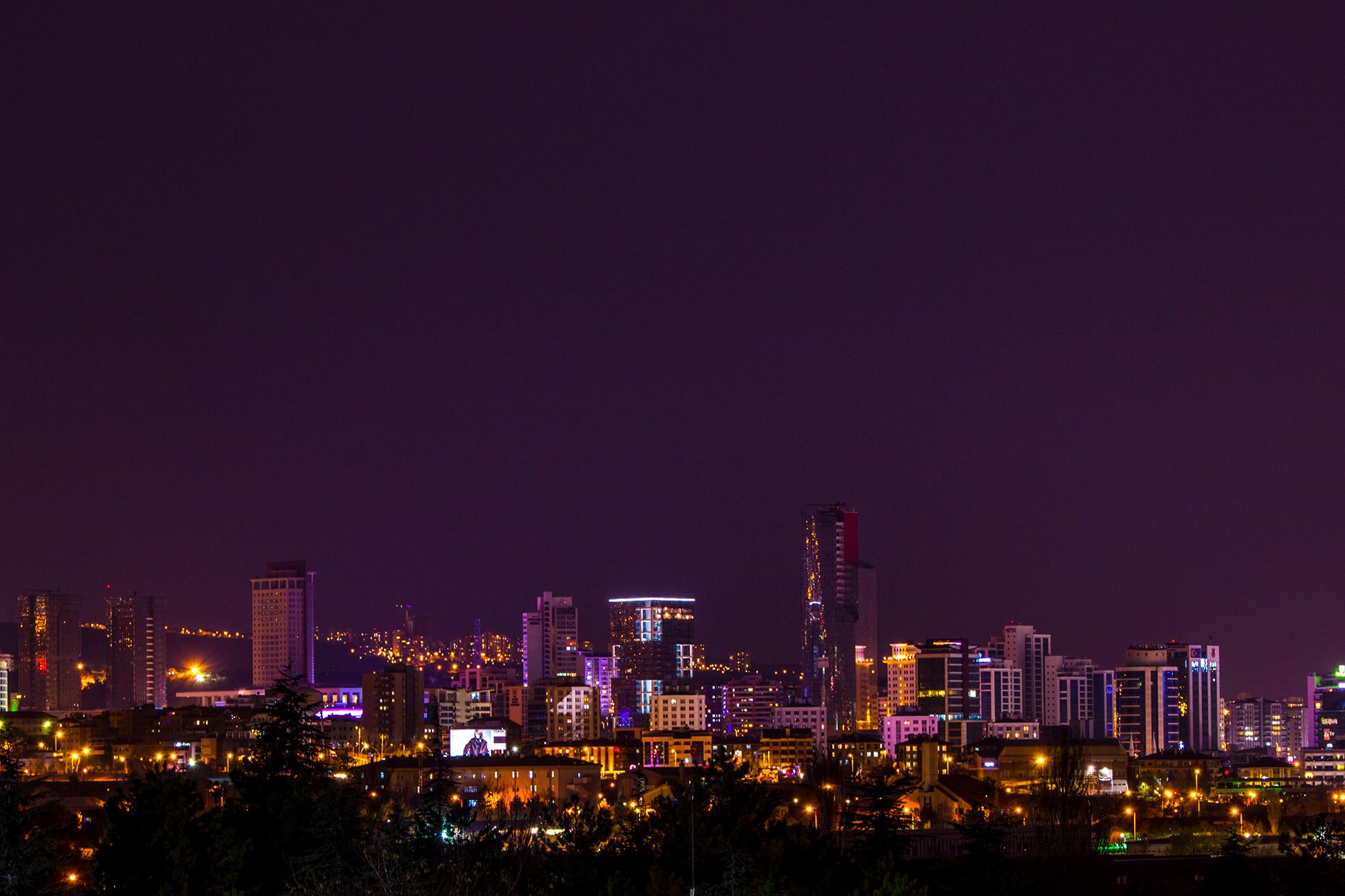 A nighttime city skyline showcasing skyscrapers uniquely lit, creating a vibrant urban landscape.