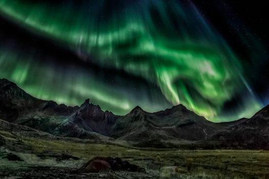 Captivating aurora borealis lighting up the night sky over rugged mountains in Myrland, Norway.