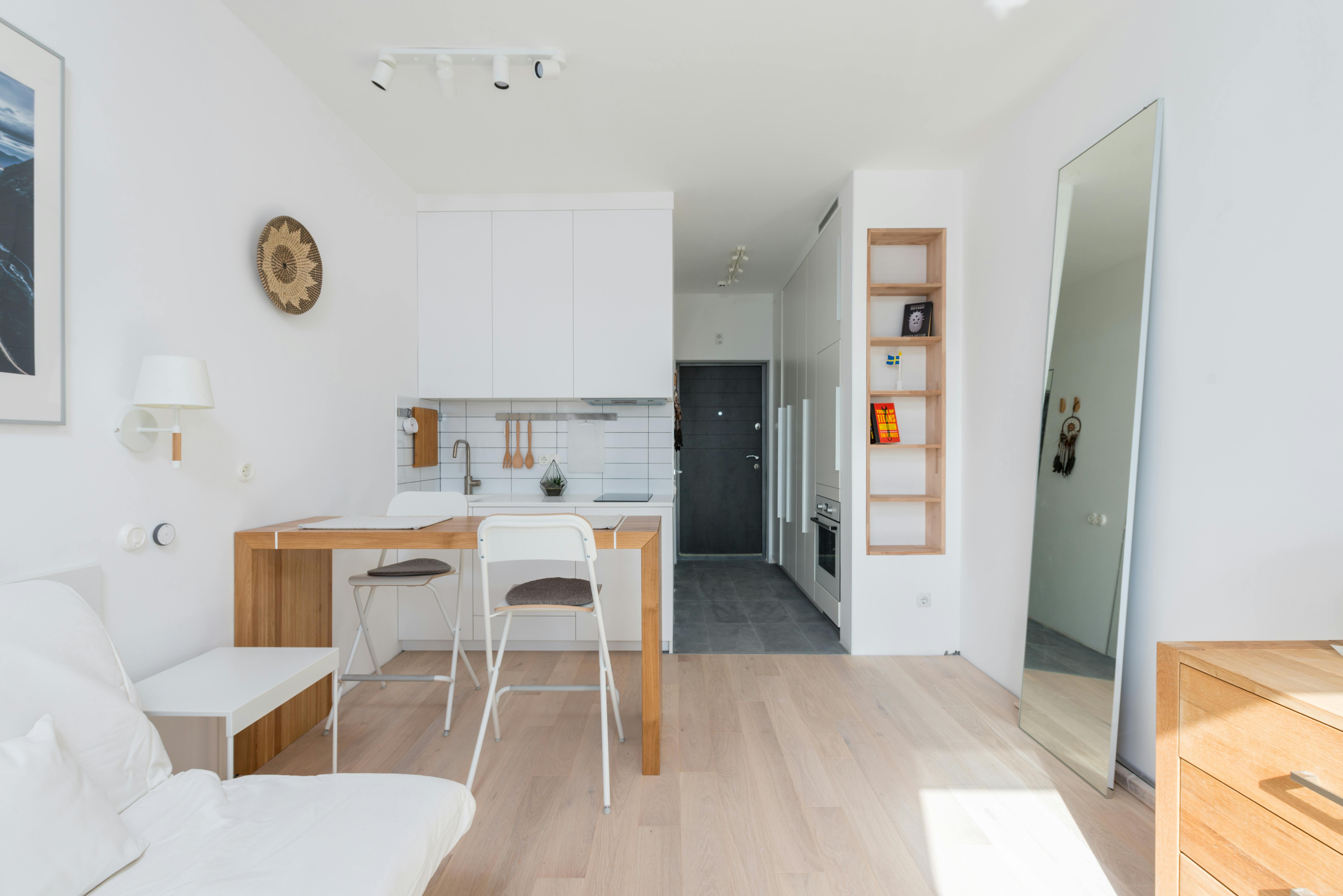 Free Modern studio apartment with white furniture and mirror in sunlight Stock Photo