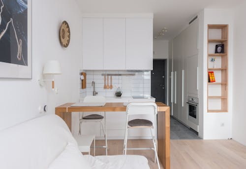 Comfortable sofa placed near wooden counter and kitchen in apartment