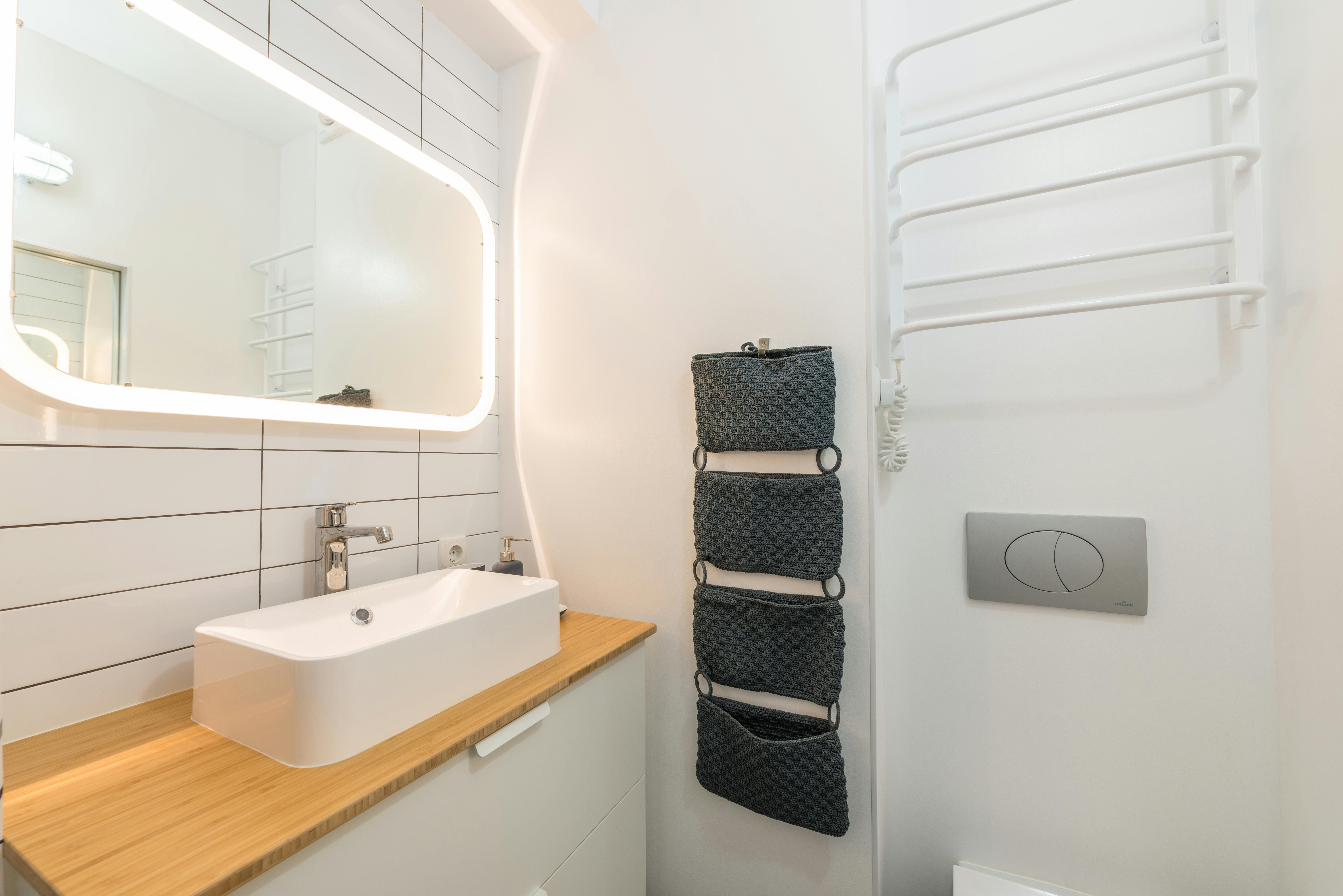 Kleines modernes Badezimmer mit Spiegelschrank, hellen Fliesen und offenen Regalen über dem WC