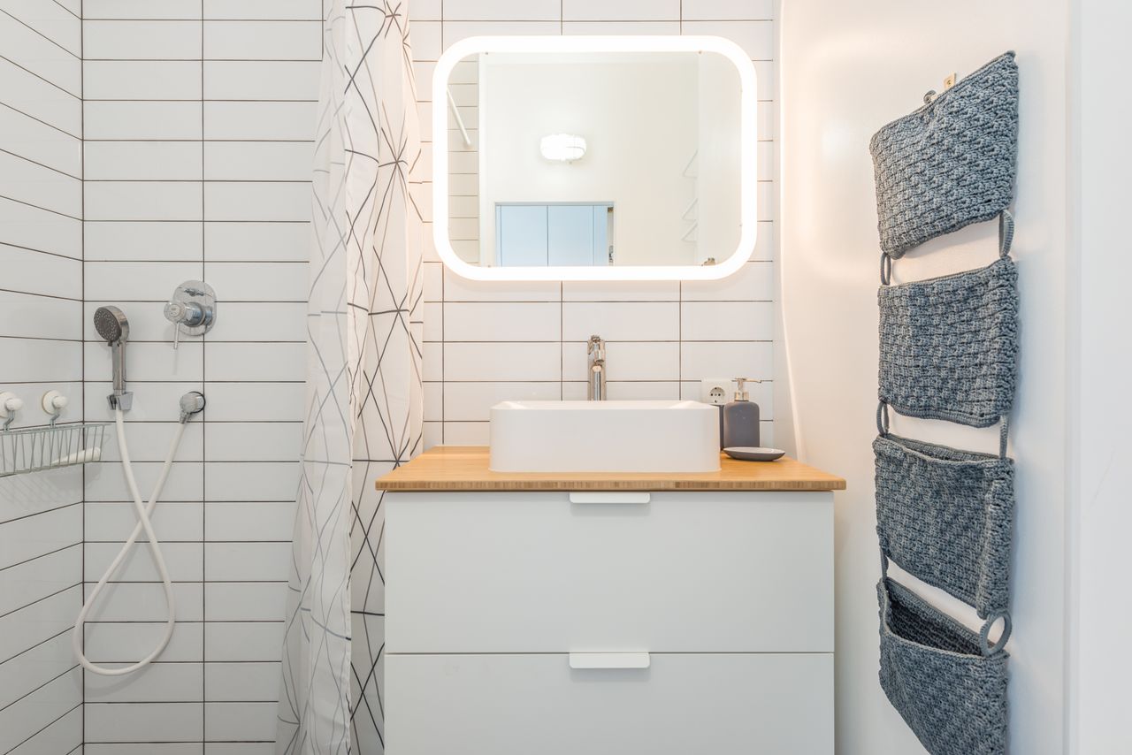 Small bright bathroom with a vessel sink and backlit mirror