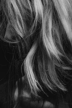 Close-up of a blonde woman's hair in a black and white artistic portrait. Grayscale photography.