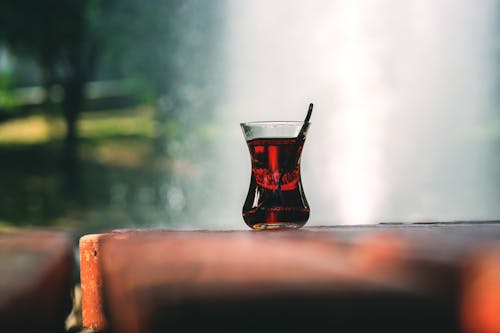 茶色の木製テーブルの上のお茶と透明なトルコのティーグラス