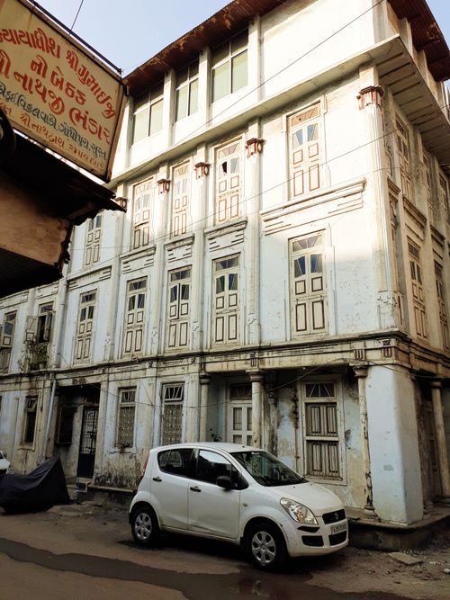 Free A white car parked next to a vintage building with intricate window designs during daylight. Stock Photo