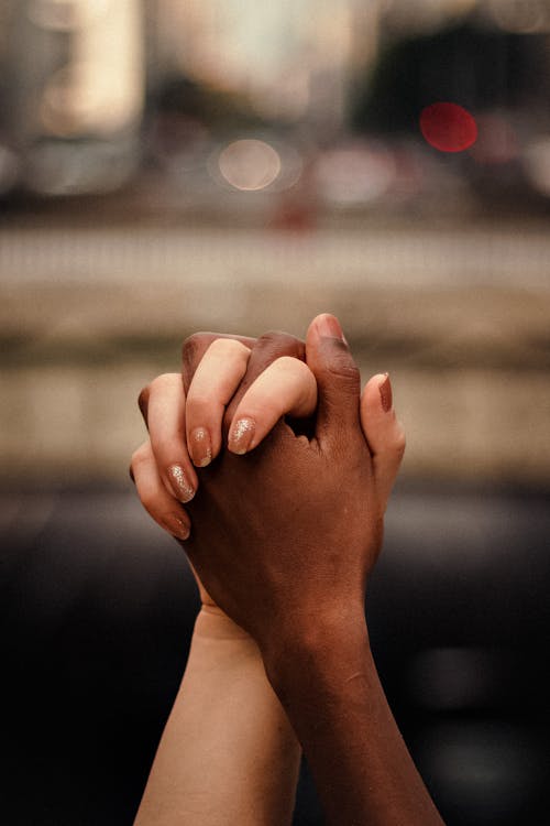 Free Multiethnic couple holding hands together in park Stock Photo