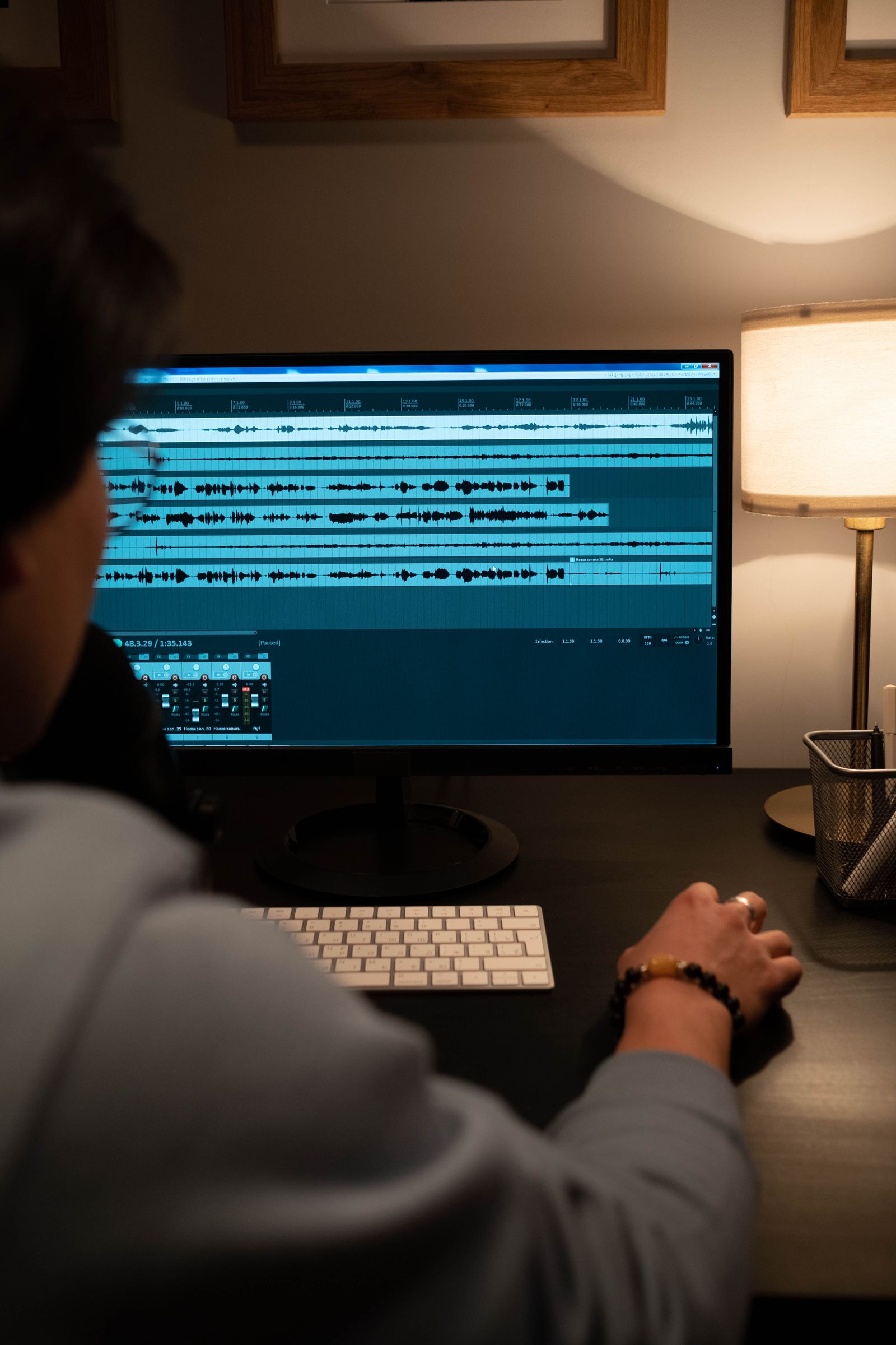 Sound engineer editing audio waveforms on a computer monitor in a recording studio