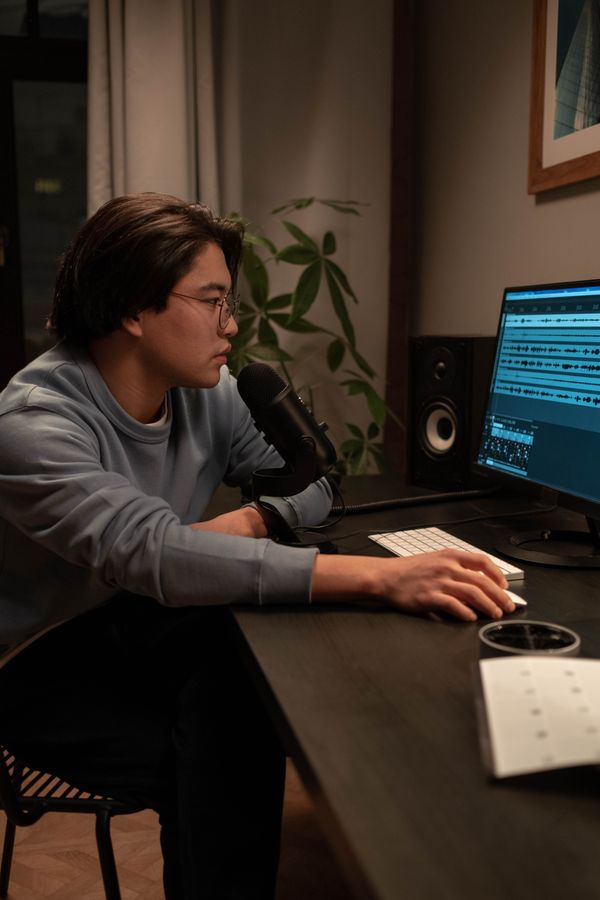 Producer working at a desk with a microphone and editing software