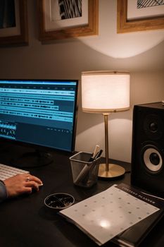 Warm home office space featuring audio editing on a computer with ambient lighting.