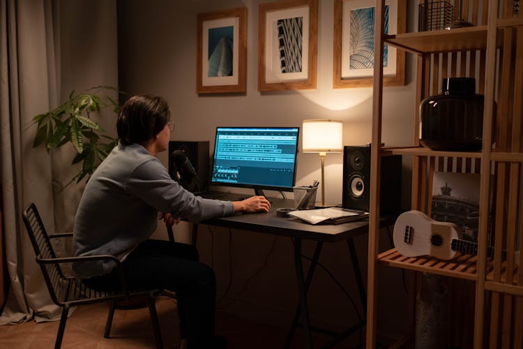 A Man In A Blue Sweater Editing On His Computer