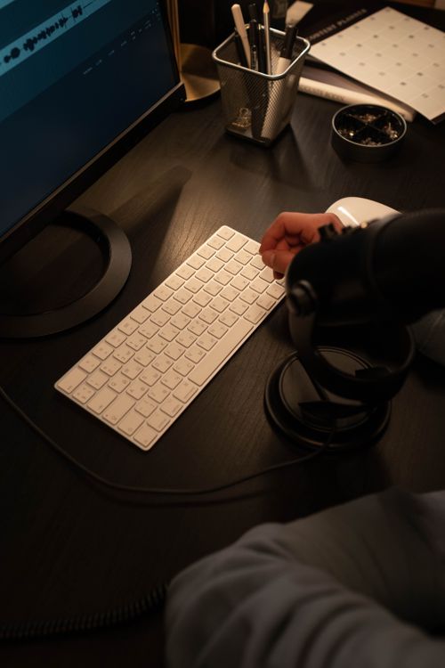 Free Close-up of a modern workspace featuring a wireless keyboard and monitor, emphasizing technology and productivity. Stock Photo