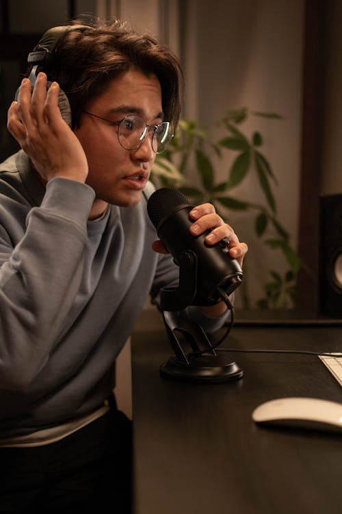 Man Sitting at the Table, Wearing Headphones and Talking to the Microphone