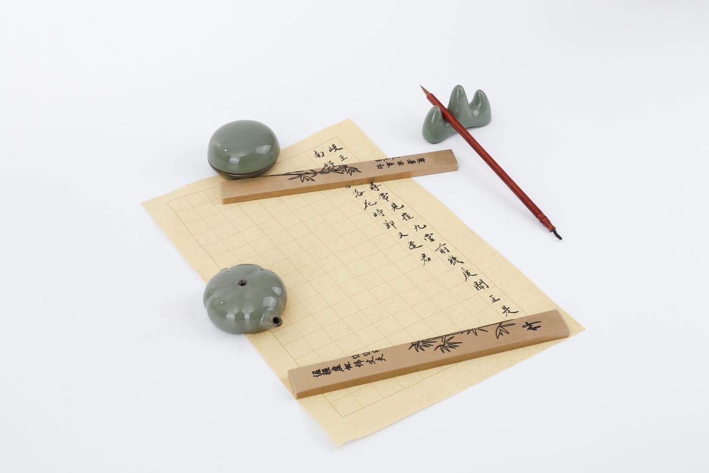 Flat lay of a traditional Chinese calligraphy set with brush, paper, and ink stones on a white background.