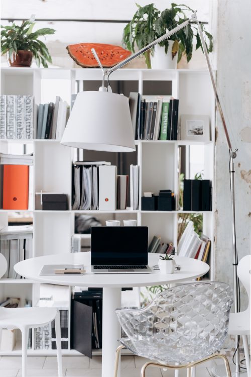 Free A stylish and minimalist home office setup featuring a laptop, books, and a modern lamp. Stock Photo