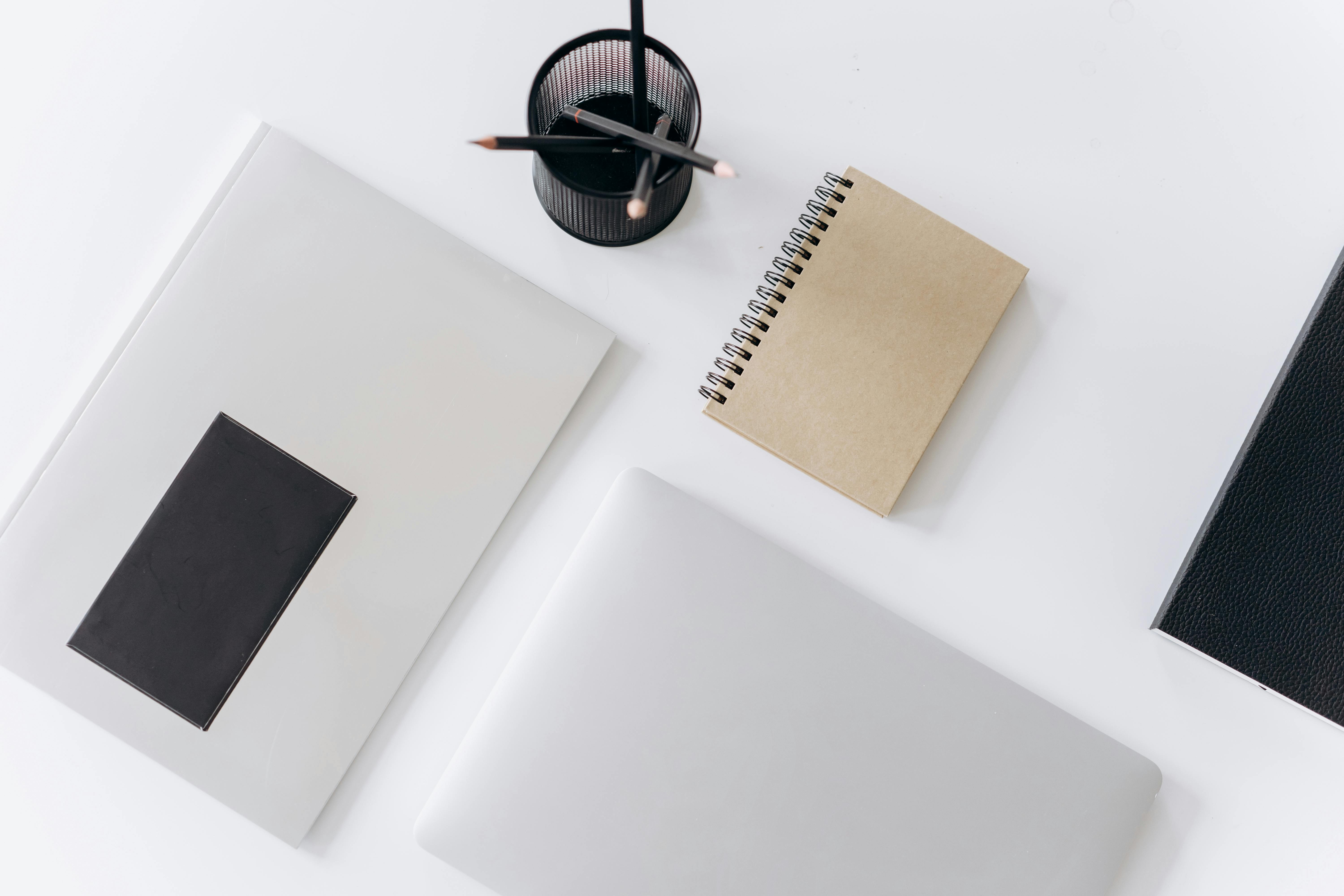 netbook with planner and jotter placed near pencils on desk