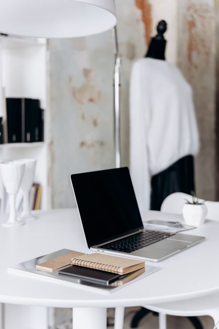 Fotomural Un espacio de trabajo minimalista con un portátil y cuadernos en una mesa redonda en un interior elegante.