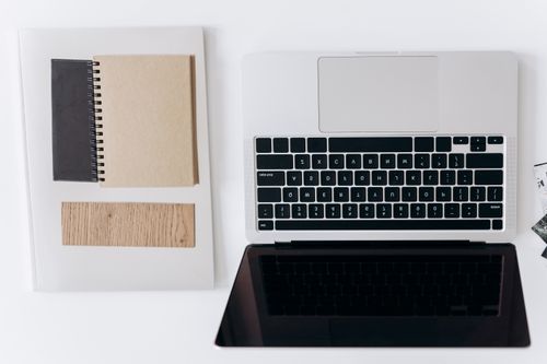 Free Top view of a minimalist workspace with a laptop and notebooks on a white desk. Stock Photo