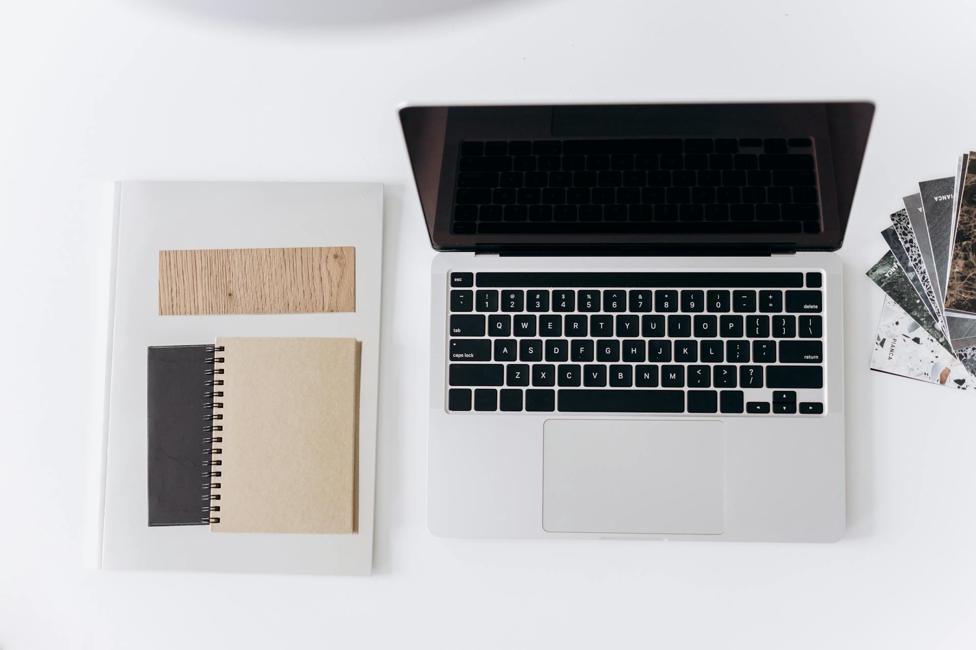 Minimalist workspace setup featuring a laptop, notebooks, and design samples for productivity