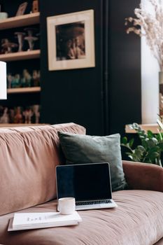 Modern home office setup featuring a laptop, mug, and throw pillow on a plush couch.