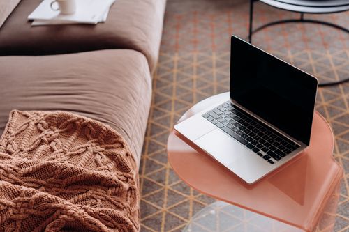 Free Laptop on a stylish side table in a cozy living room with soft furnishings. Stock Photo