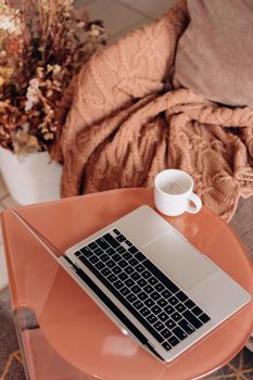 Warm and inviting workspace featuring a laptop and coffee on a stylish table.