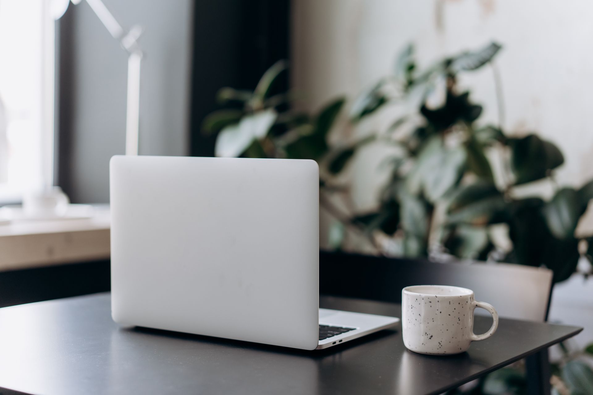 A minimalist workspace featuring a closed laptop and a coffee cup on a table, offering a serene and focused atmosphere.