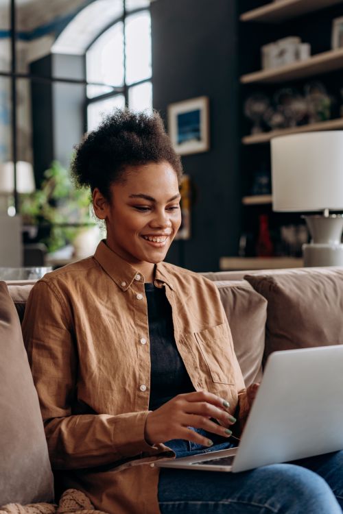 Free A cheerful woman working on a laptop in her modern home office setting. Stock Photo