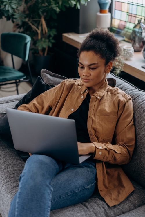 Free Focused woman in brown jacket working on a laptop at home. Stock Photo