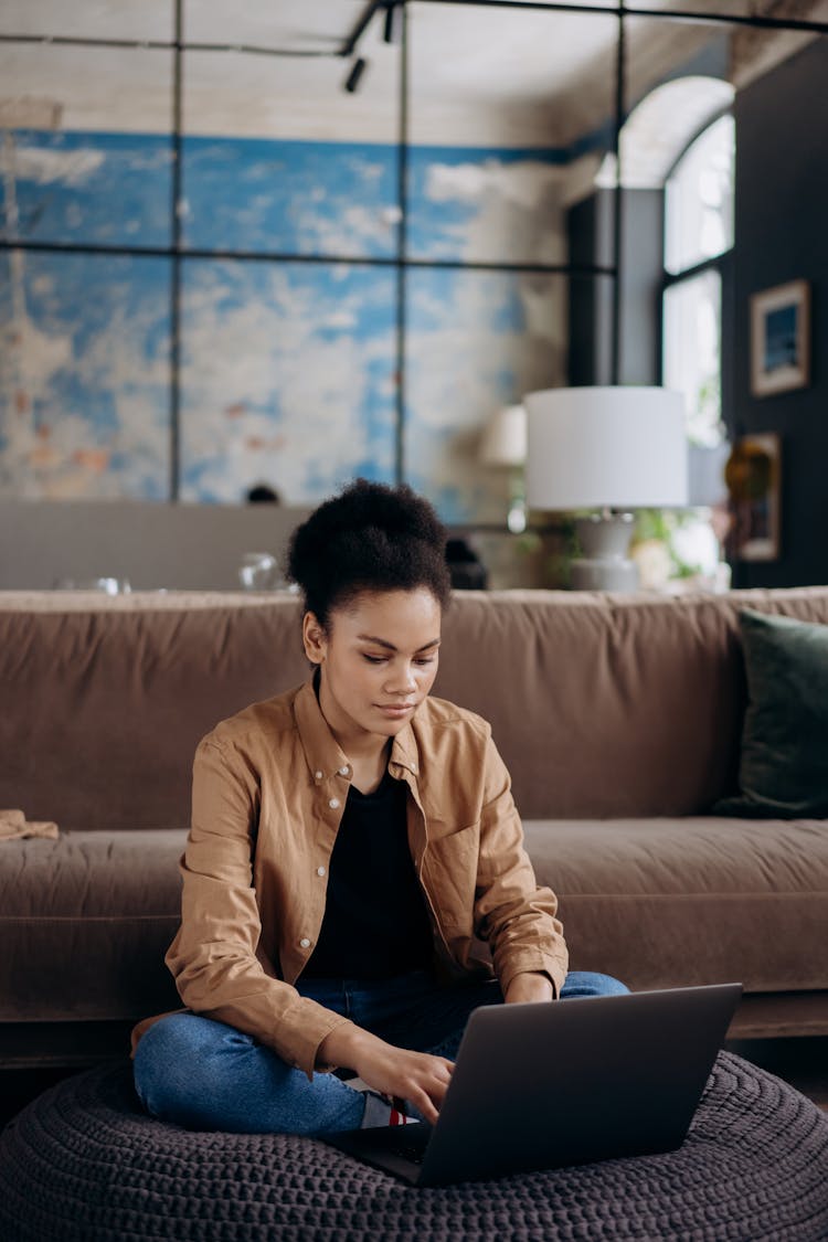 Woman In Brown Jacket Sitting On Knitted Floor Cushion