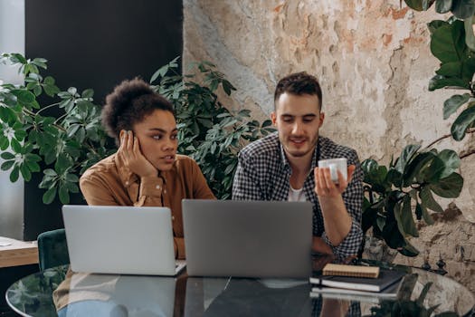 Two colleagues collaborate in a plant-filled, cozy workspace.