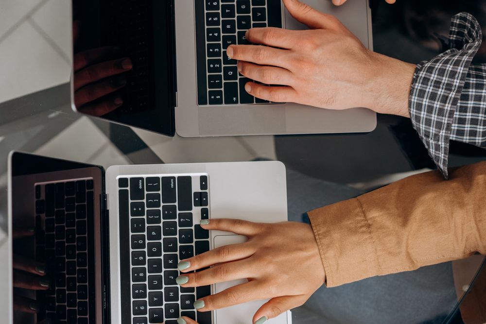 Two people working side by side on laptops, photo by Mikhail Nilov on Pexels