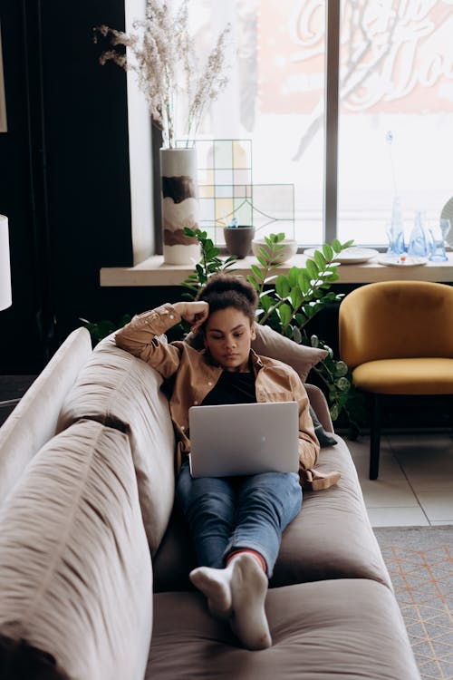 Woman Lying on Sofa While Using a Laptop