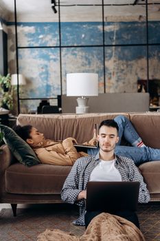 Young adults working and relaxing in a cozy home setting with laptops and casual vibes.