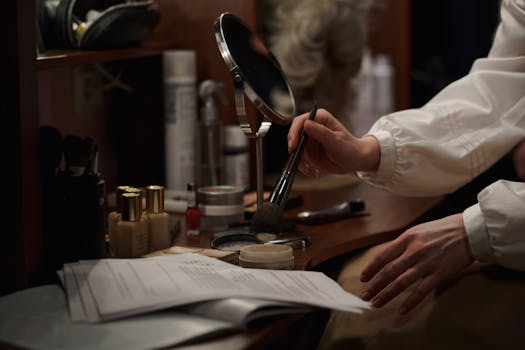 A woman applies makeup in a dressing room, focusing on artistry and glamour backstage.