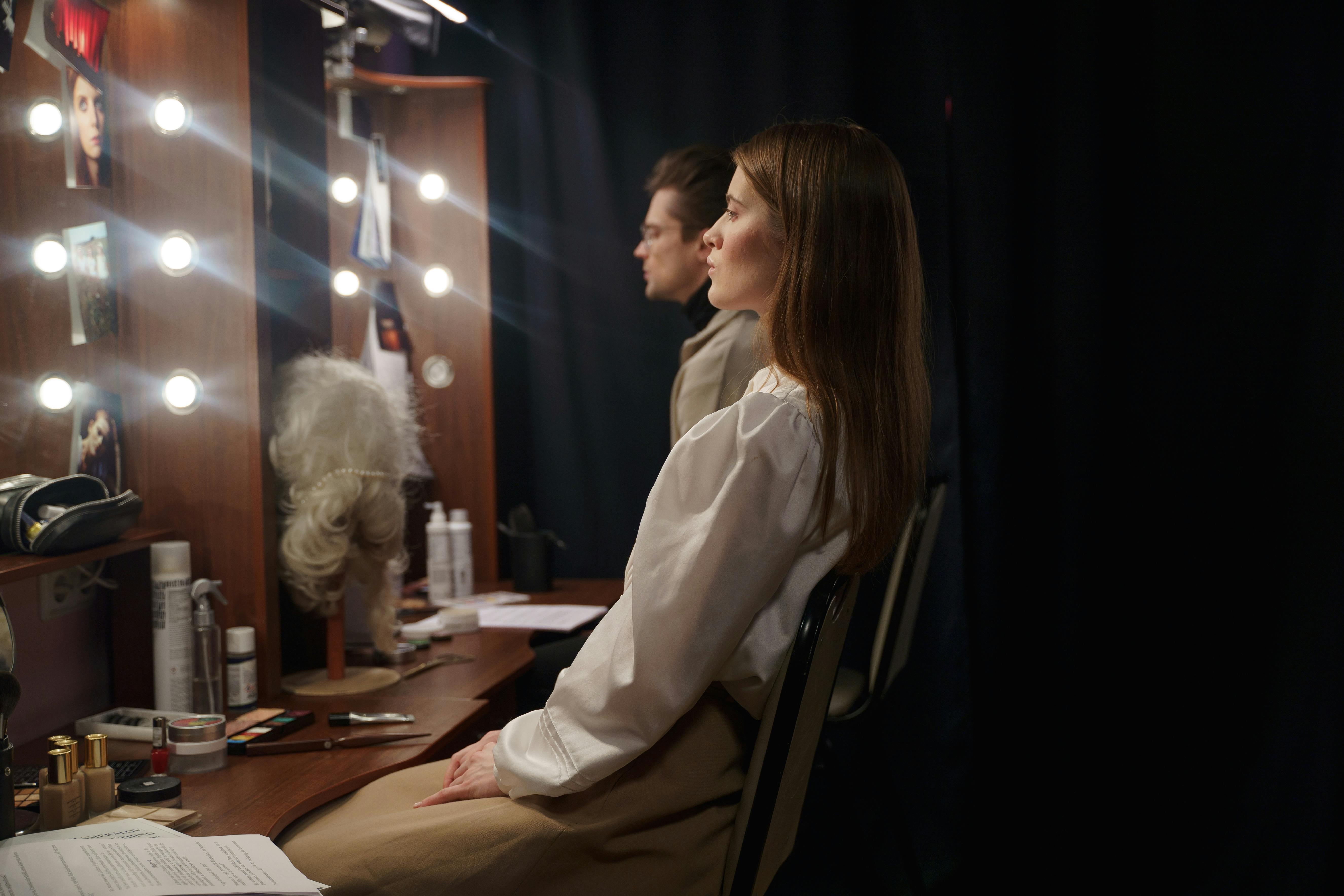 man and woman sitting infront of a mirror