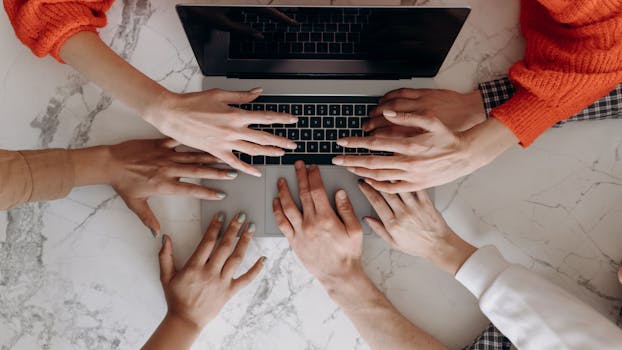 Overhead view of a diverse group working together on a laptop, highlighting collaboration.