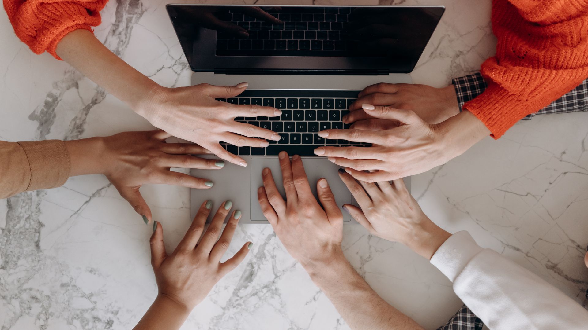 Overhead view of a diverse group working together on a laptop, highlighting collaboration.