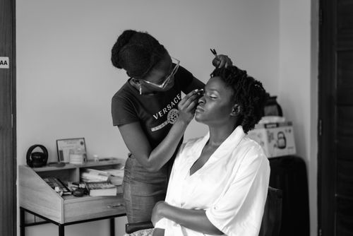 Free African American woman having makeup applied in monochrome setting. Stock Photo