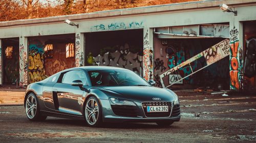 Free Sleek Audi R8 parked in an urban setting with a vivid graffiti background. Stock Photo