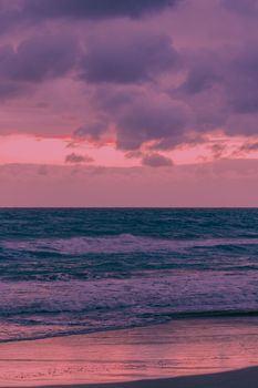 A serene beach scene with a dramatic cloudy sky and twilight hues over the ocean.