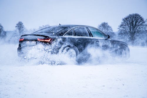 Free 
A Black Audi Car Driving on a Snow Covered Field Stock Photo