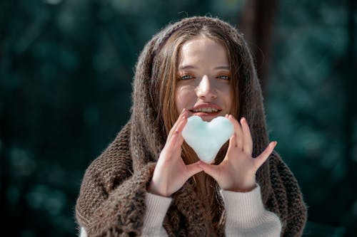 A Young Woman with Headscarf Holding a Heart Shaped Snow