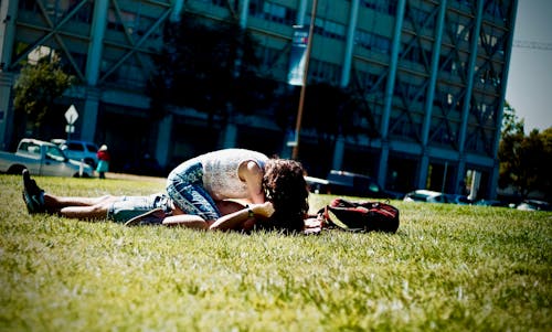 Free Man and Woman Lying on Green Field Stock Photo