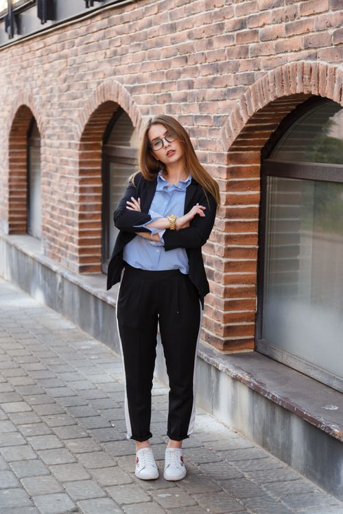 Free Professional woman in business attire posing confidently on a sidewalk near brick arches. Stock Photo