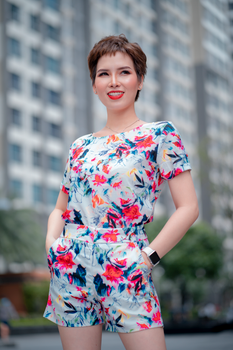 A fashionable woman poses confidently in a colorful floral jumpsuit on a city street.