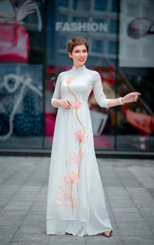 Free Asian woman modeling an elegant white ao dai with floral designs. Stock Photo