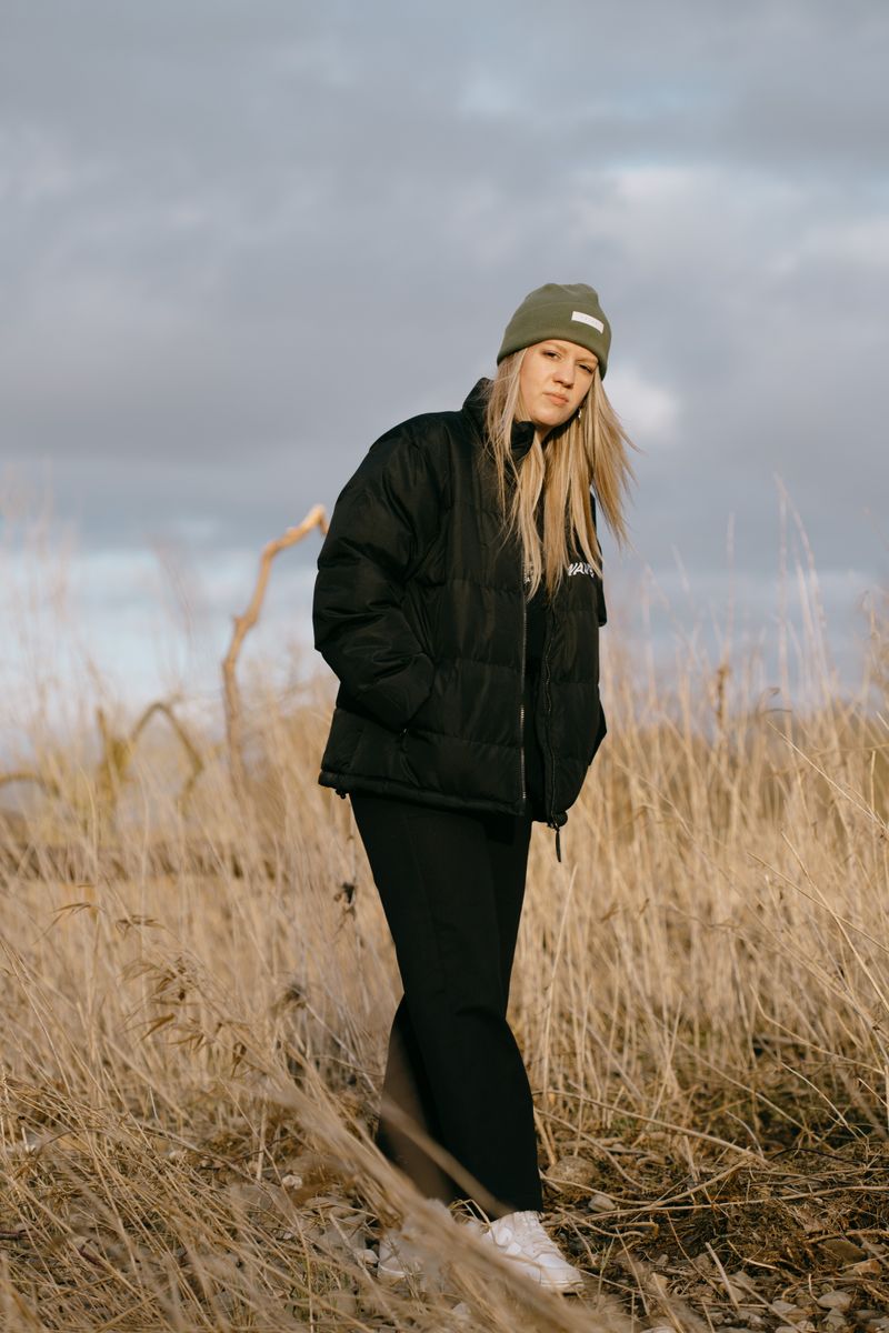 Woman in a puffer coat and beanie standing in fields